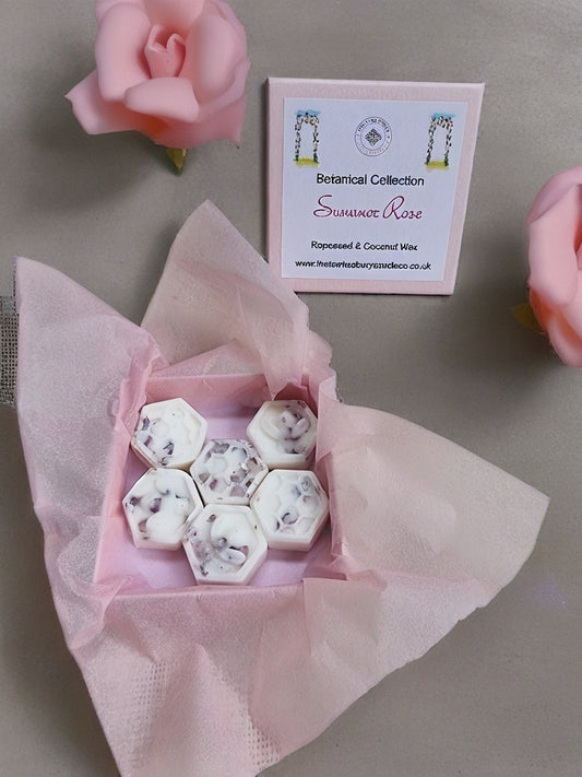 Box of white hexagonal botanical wax melts with a pink rose and product label on a gray background