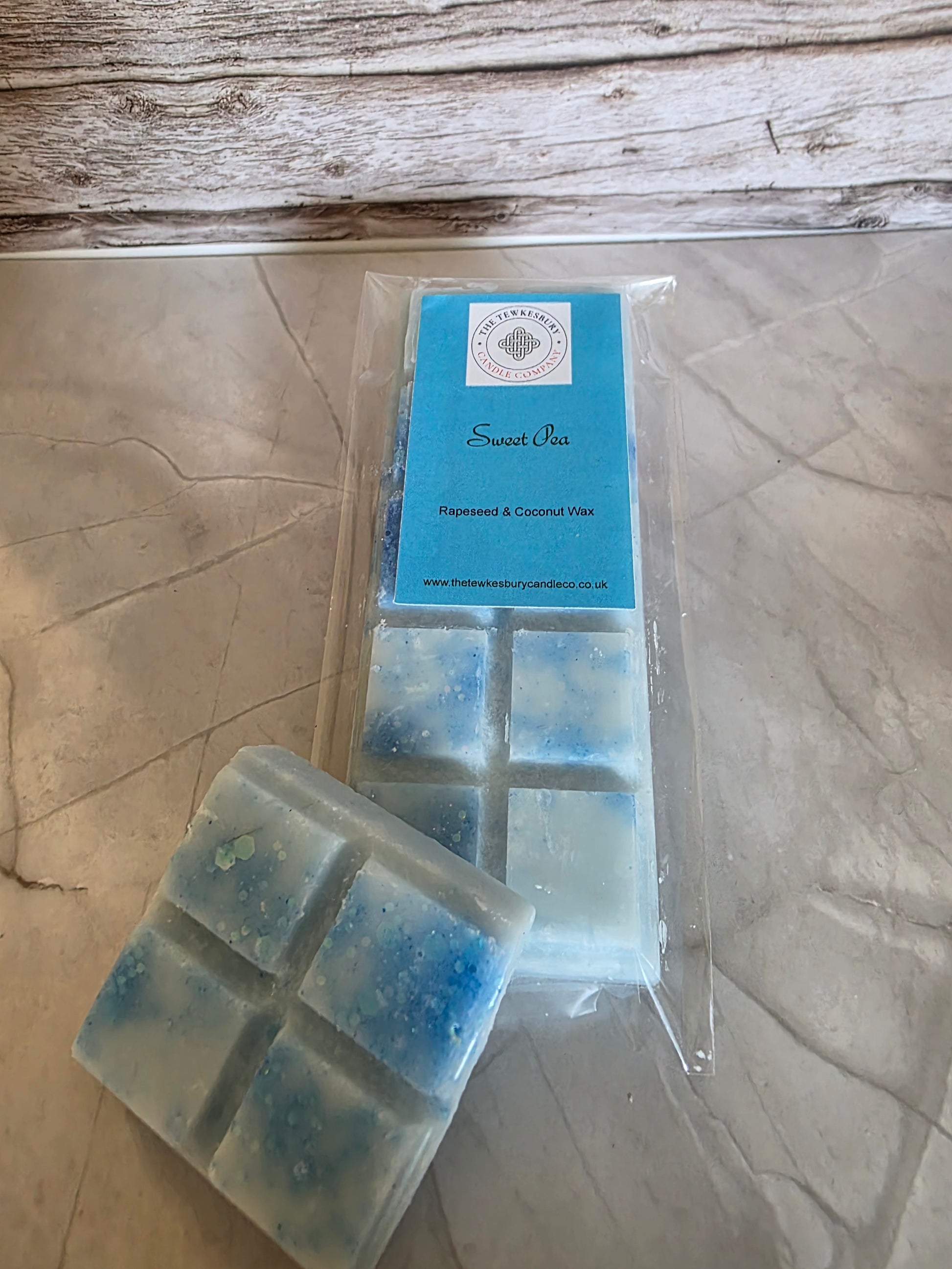 Packaged wax melts with a blue label on a wooden surface