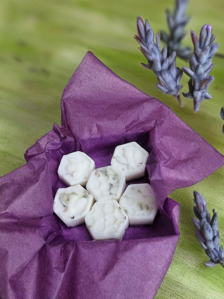 White hexagonal wax melts in a purple bag with lavender flowers on a green background
