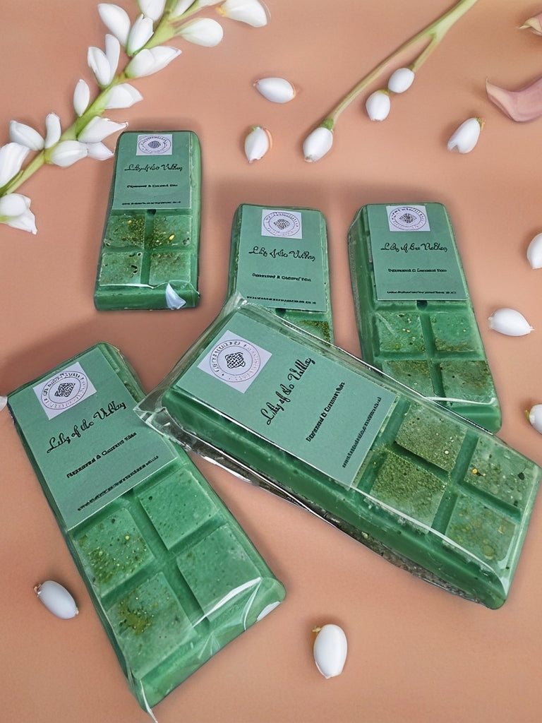 Green wax melts in packaging with 'Lily of the Valley' branding on a beige background with white flowers.