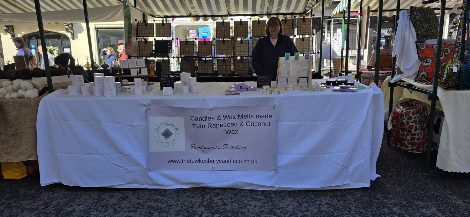 Table with candles and wax melts at an outdoor market stall.
