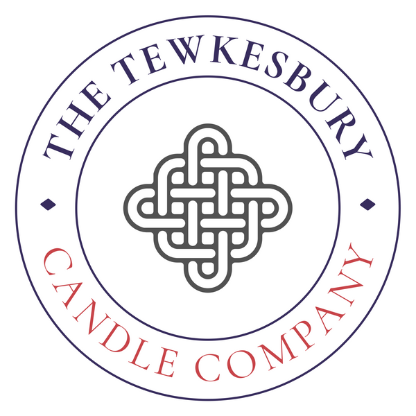 A circular logo for The Tewkesbury Candle Company, featuring a central Celtic knot design with navy blue and red text on a white background.